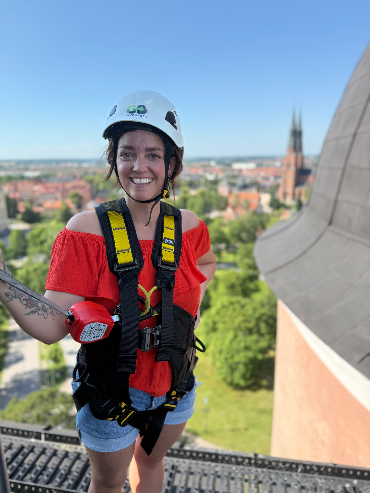 Gäst i säkerhetssele och hjälm på taket av Uppsala slott med domkyrkan i bakgrunden